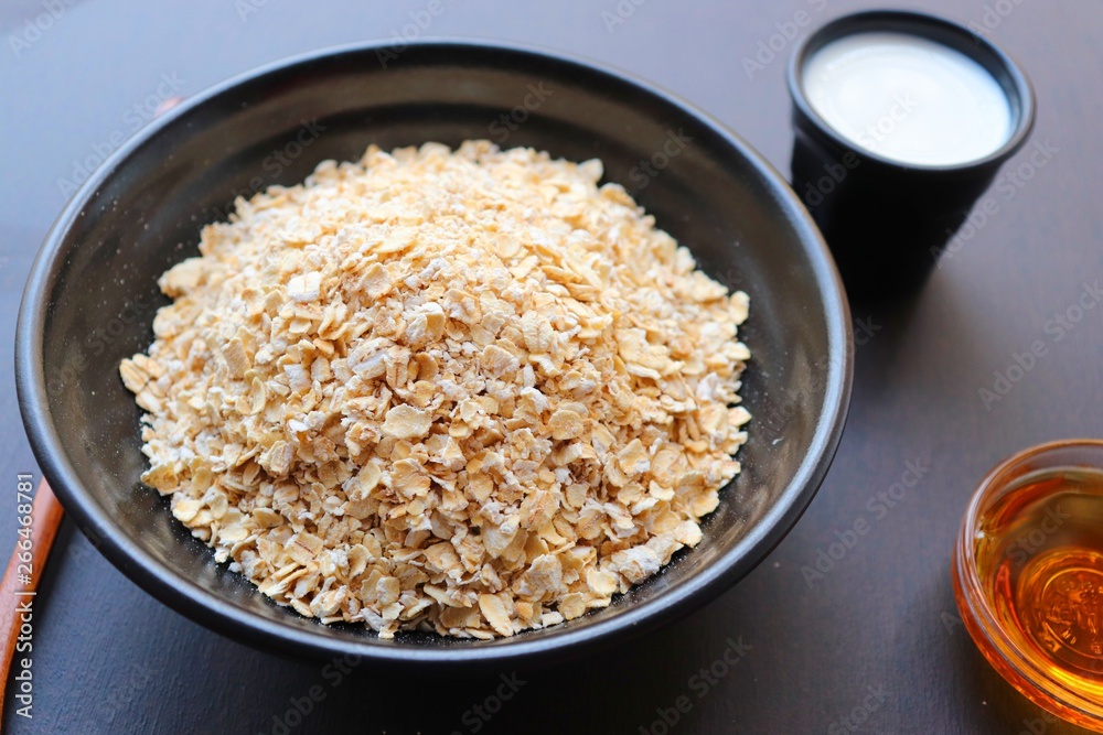 Healthy breakfast with oat flakes, natural milk and honey. black wooden background with cloth. Top view. recipe ingredients. Healthy breakfast with oat flakes, natural milk and honey. black wooden background with cloth. Top view. recipe ingredients.