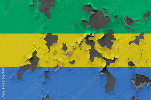 Close up grungy, damaged and weathered Gabon flag on wall peeling off paint to see inside surface.