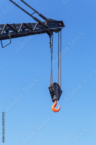 a fragment of a crane lifting mechanism with ropes and a hook against a blue sky