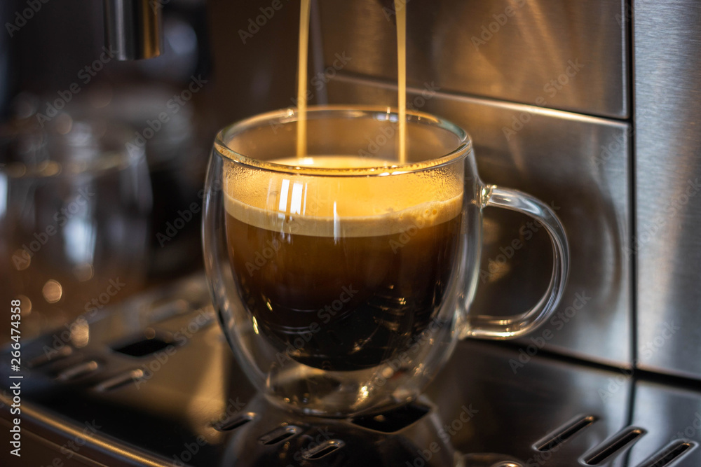 glass mugs with coffee in a coffee machine,cooking process, close-up