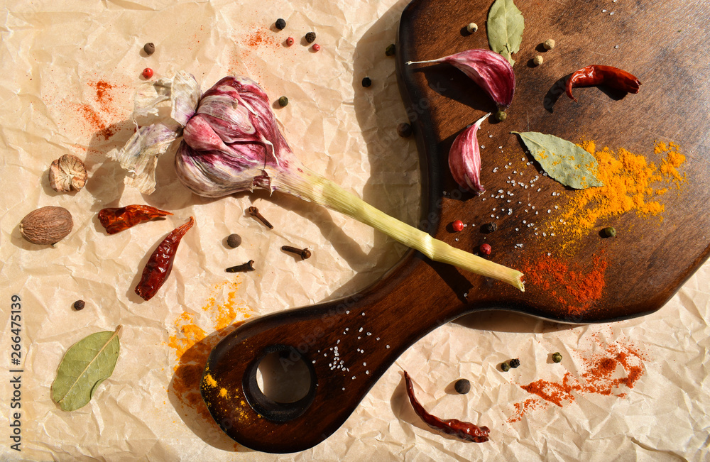 Garlic and various spices for dressing dinner dishes on a wooden board. Dark wood, bay leaf, chili pepper, nutmeg. Top close up view flat lay food vegan photo Garlic and various spices for dressing dinner dishes on a wooden board. Dark wood, bay leaf, chili pepper, nutmeg. Top close up view flat lay food vegan photo