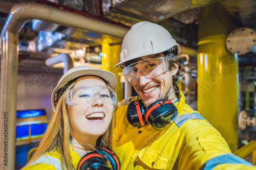Man and woman in a yellow work uniform, glasses, and helmet in an industrial environment, oil Platform or liquefied gas plant