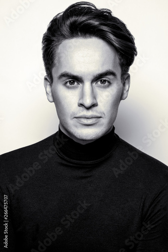 Male beauty concept. Portrait of handsome young man with stylish haircut posing over gray background. Perfect hair & skin. Close up. Studio shot