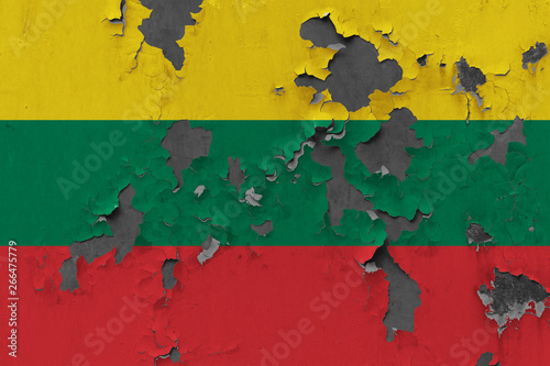 Close up grungy, damaged and weathered Lithuania flag on wall peeling off paint to see inside surface.