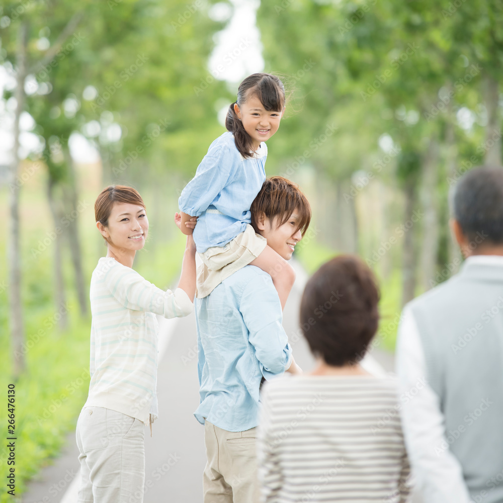 一本道で肩車をする親子と祖父母 一本道で肩車をする親子と祖父母