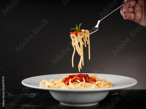 Hand holding pasta wrapped on fork