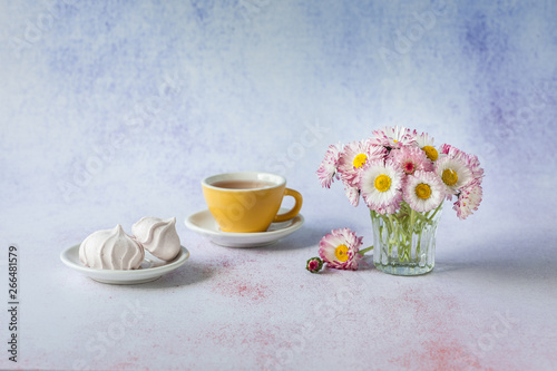 Fototapeta Naklejka Na Ścianę i Meble -  Cup of tea with white meringues  and daisies in vase. Morning surprise. Minimalism, soft focus, place for text, close up.