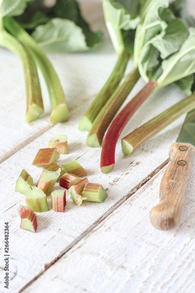 Fresh rhubarb stems cut with knife on a bright background, flat lay Fresh rhubarb stems cut with knife on a bright background, flat lay