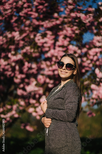 Bussines woman in blazer and sunglasses stand in front of pink tree