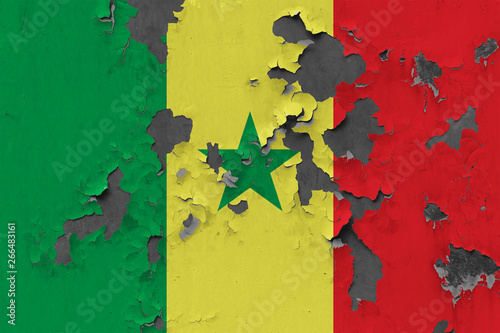 Close up grungy, damaged and weathered Senegal flag on wall peeling off paint to see inside surface.