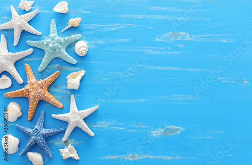 vacation and summer concept with starfish and seashells over blue wooden background. Top view flat lay © tomertu