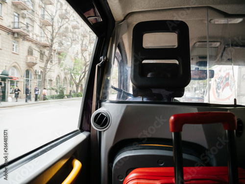 Defocused view from hackney carriage taxi cab in Baku Azerbaijan with red luggage inside and street view with people silhouette