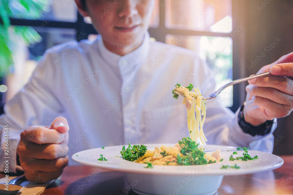 Handsome man with fork enjoy eating spaghetti carbonara in restaurant. Handsome man with fork enjoy eating spaghetti carbonara in restaurant.
