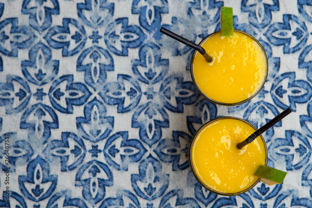 Fresh tropical fruit smoothie mango juice on blue background. Copy space. Top view.