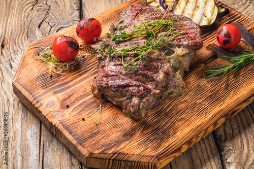 Juicy medium rare beef steak on wooden board with herbs.