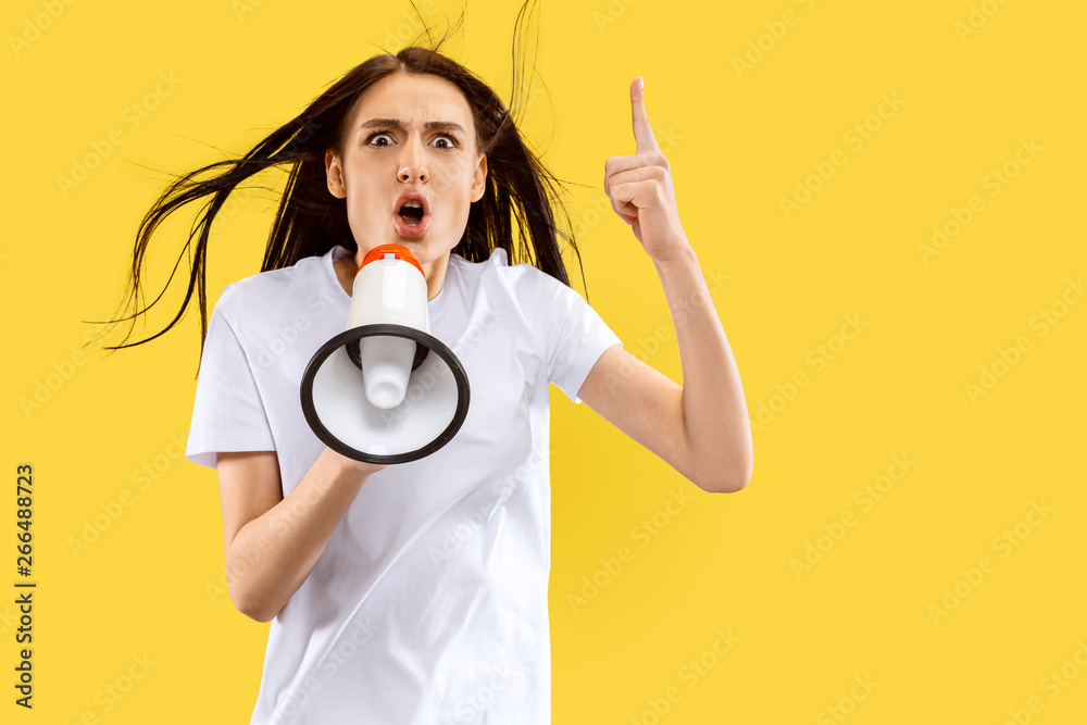 Screaming girl with the mouthpiece. Beautiful female half-length portrait isolated on yellow studio background. Young smiling woman. Negative space. Facial expression, human emotions concept. Screaming girl with the mouthpiece. Beautiful female half-length portrait isolated on yellow studio background. Young smiling woman. Negative space. Facial expression, human emotions concept.