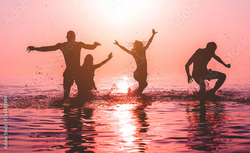 Vászonkép Happy friends jumping inside water on tropical beach at sunset - Group of young