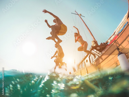 Fototapeta Happy friends diving from sailing boat into the sea - Young people jumping insid