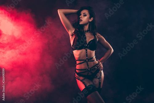 Portrait of stunning gorgeous charming attractive perfect sporty wavy-haired lady wearing swordbelt teasing touching hair isolated over black red light background