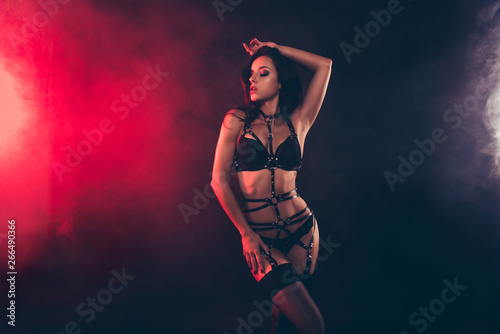 Portrait of nice winsome sweet lovely magnificent stunning charming attractive perfect sporty fit wavy-haired lady wearing swordbelt teasing posing isolated over black red light background