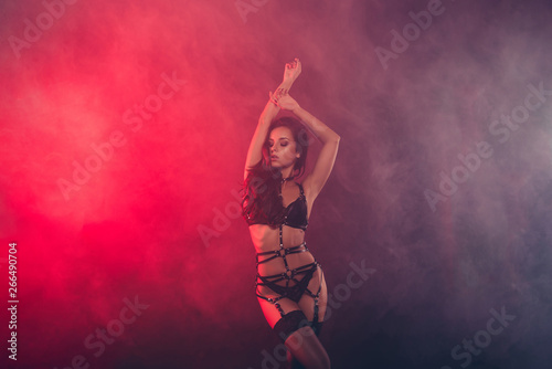 Nice attractive fascinating charming sportive perfect figure wavy-haired lady wearing swordbelt teasing posing closed eyes enjoying lifestyle night club clubber isolated on red light black background © deagreez