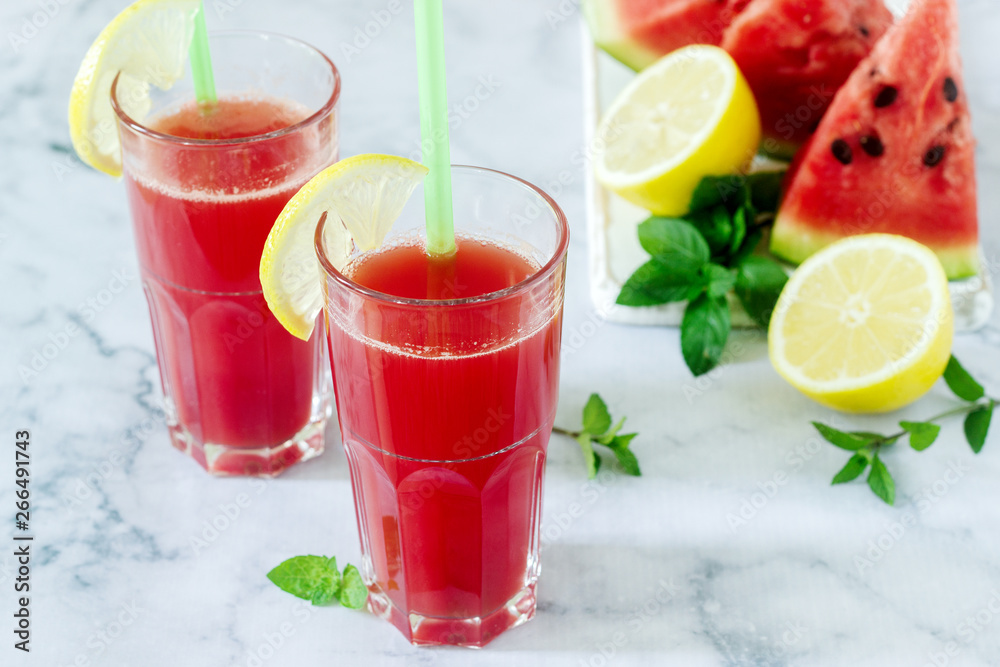 Cold watermelon lemonade with mint and lemon in glass glasses and ingredients for lemonade on a light background. Cold watermelon lemonade with mint and lemon in glass glasses and ingredients for lemonade on a light background.
