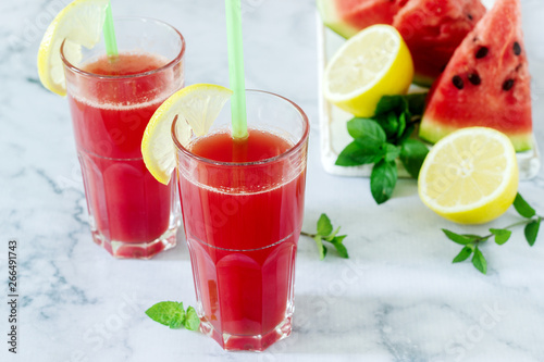 Cold watermelon lemonade with mint and lemon in glass glasses and ingredients for lemonade on a light background.