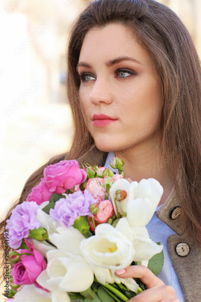 Beautiful young woman with bouquet of flowers outdoors