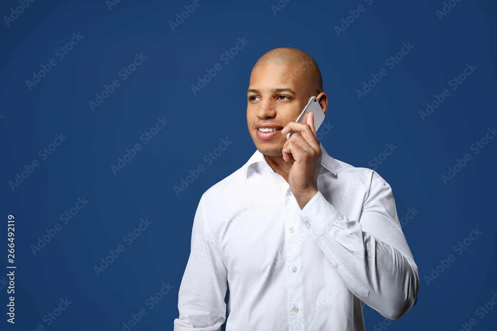Handsome African-American man talking by phone on color background Handsome African-American man talking by phone on color background