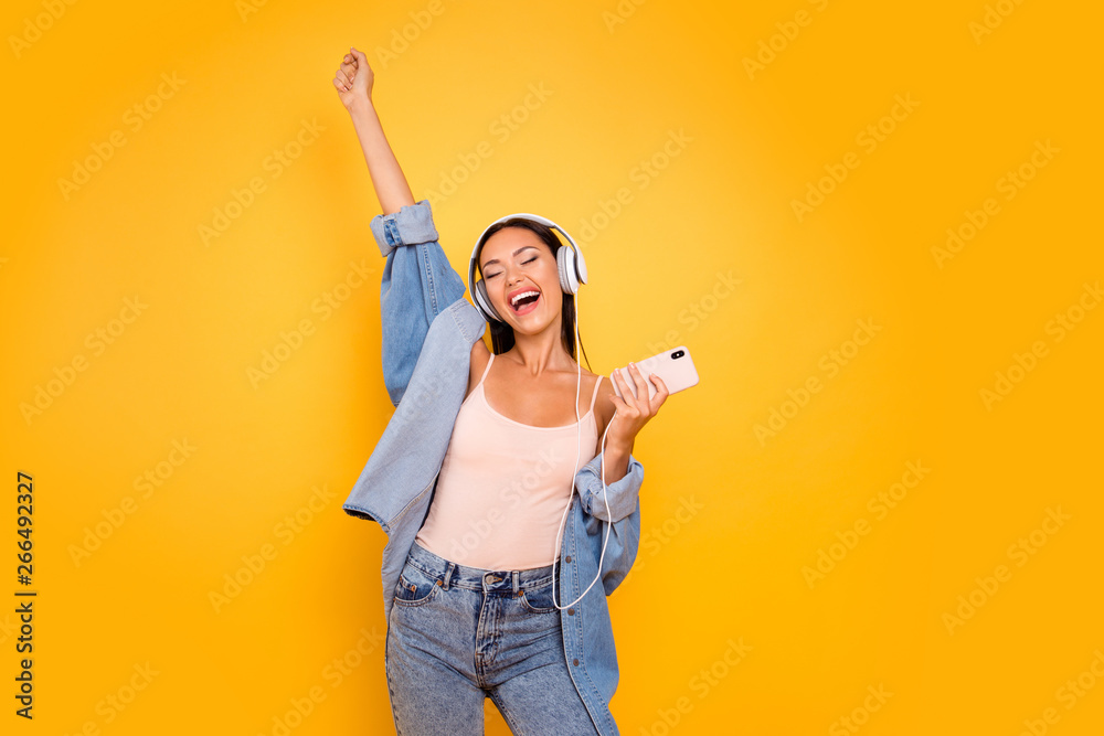 Close up photo beautiful she her model lady trendy earflaps eyes closed  overjoyed sunny day good playlist telephone wear casual pastel tank-top jeans  denim jacket isolated yellow bright background Stock Photo