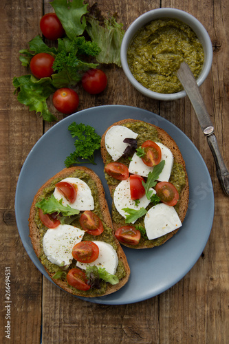 Pesto toast with mozzarella cheese, cherry tomatoes, bruschetta toast on wooden background. Healthy breakfast ,snack.