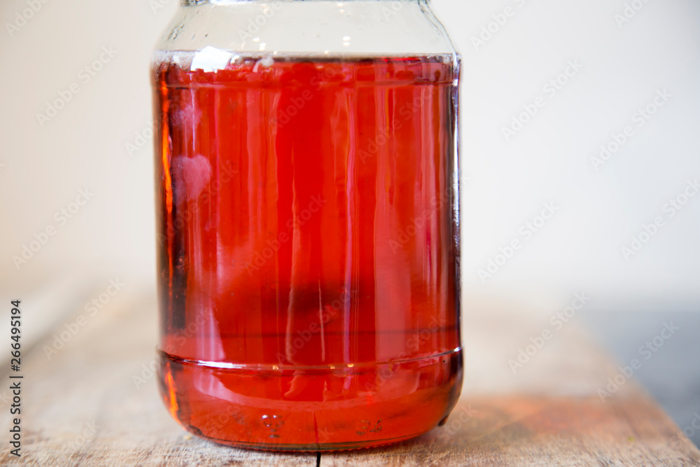 Homemade quince jelly in a glass jar with a black lid sitting on a wooden chopping board. It is made with imperfect, organic homegrown fruit. The clear ruby red color comes from the tannins. Homemade quince jelly in a glass jar with a black lid sitting on a wooden chopping board. It is made with imperfect, organic homegrown fruit. The clear ruby red color comes from the tannins.