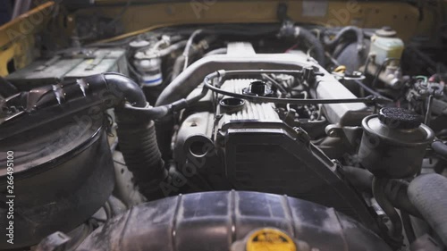 Close up at the hand of a mechanic while removing the oil cap of a car engine