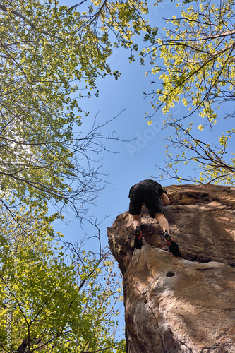 young free climber on a steep boulder in the forest