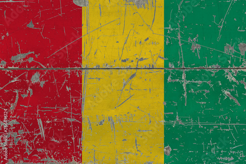 Grunge Guinea flag on old scratched wooden surface. National vintage background.
