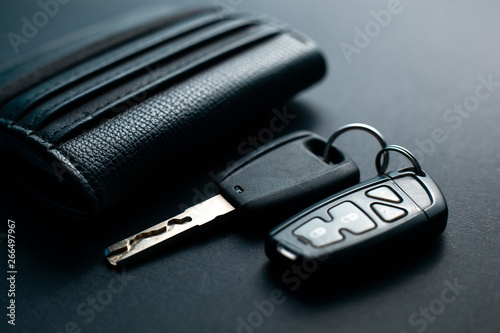 Black leather wallet with car key on a black background