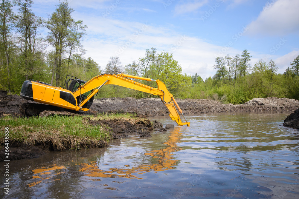 Big excavator puts its shovel under the water to dig make river canal more deep and clean it of different garbage Big excavator puts its shovel under the water to dig make river canal more deep and clean it of different garbage