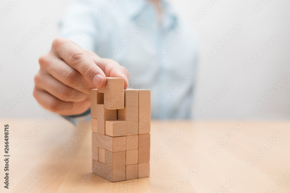 Man's hand adding the last missing wooden block into place. Business success concept. Man's hand adding the last missing wooden block into place. Business success concept.