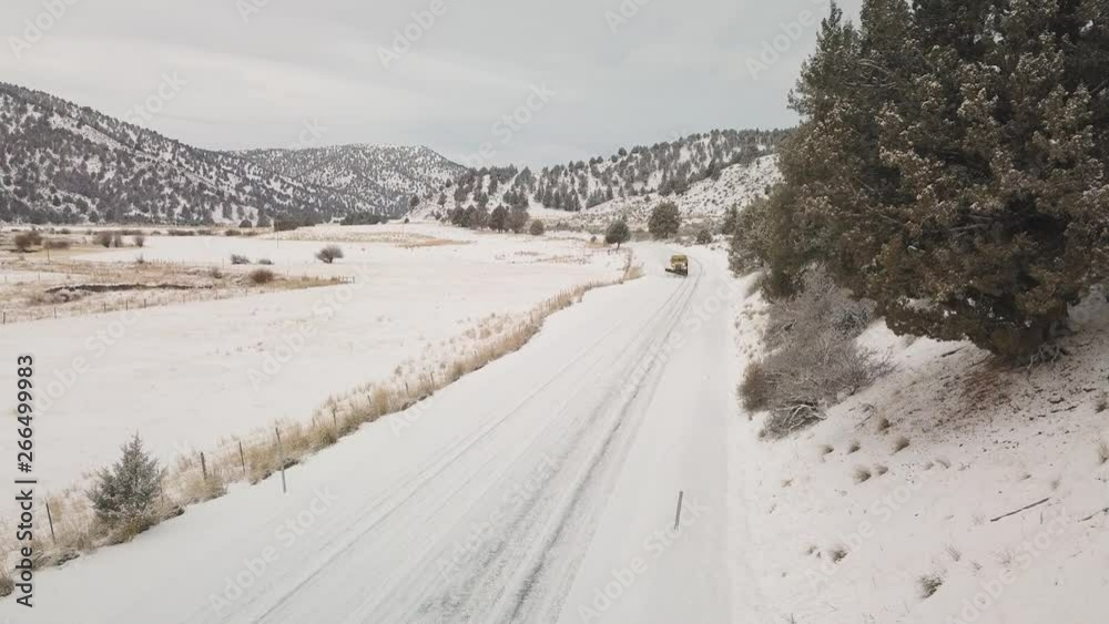 A yellow truck with a shovel installed in the front moves snow from a road A yellow truck with a shovel installed in the front moves snow from a road