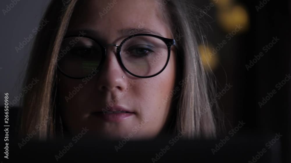 Slide shot from right to left of a young woman looking intently at screen of a laptop Slide shot from right to left of a young woman looking intently at screen of a laptop