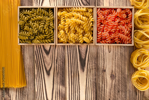 Multi-coloured pasta in the form of spirals lies in square wooden boxes that stand on a table