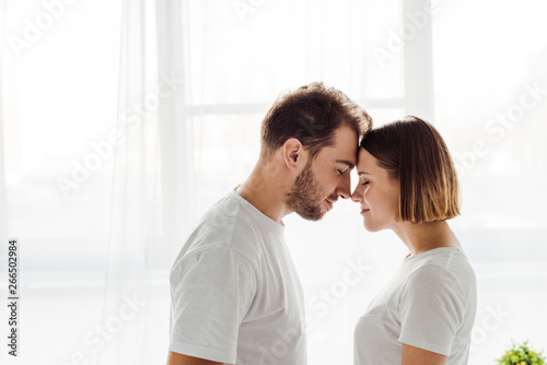 side view of happy loving couple standing with closed eyes at home