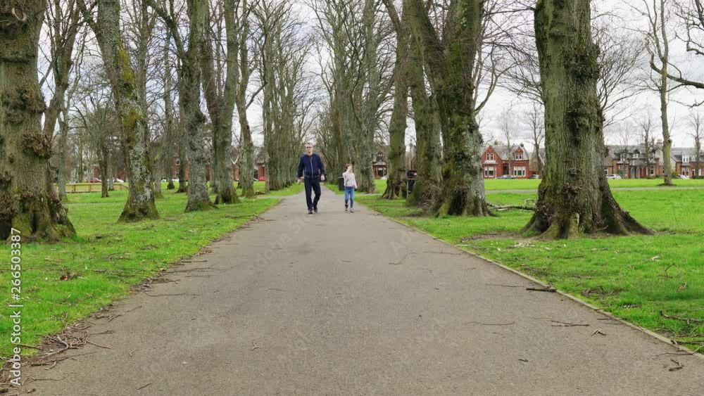 A Dad and his little girl walking through the park A Dad and his little girl walking through the park