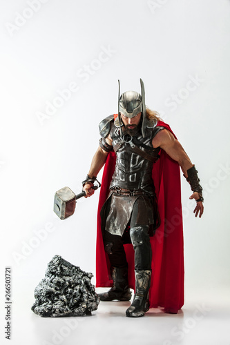 Cuadro en lienzo Long hair and muscular male model in leather viking's costume with the big hammer cosplaying Thor isolated on white studio background