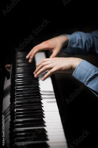 two male hands on the piano. palms lie on the keys and play the keyboard instrument in the music school. student learns to play. hands pianist. black dark background. vertical