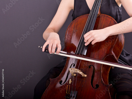  Young girl playing the cello in the dark. Cellist