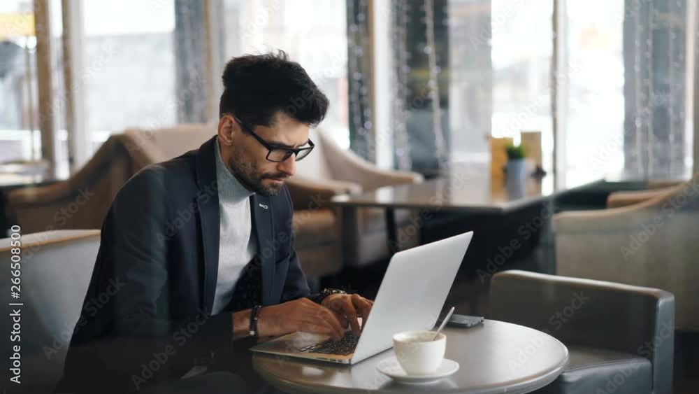 Corporate manager handsome middle-aged man in trendy suit is working in cafe during lunch break using modern laptop typing looking at computer screen. Corporate manager handsome middle-aged man in trendy suit is working in cafe during lunch break using modern laptop typing looking at computer screen.