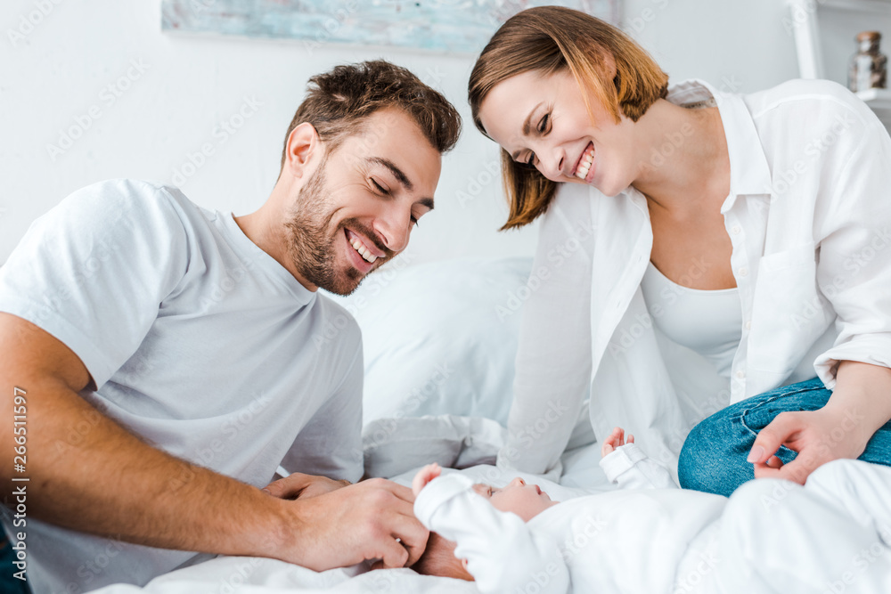 Happy young parents looking at baby on bed Happy young parents looking at baby on bed