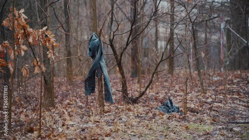 Abandoned or lost clothes hanging on a tree on a winter day. A concept of murder mystery and missing person. Hand-held shot. photo