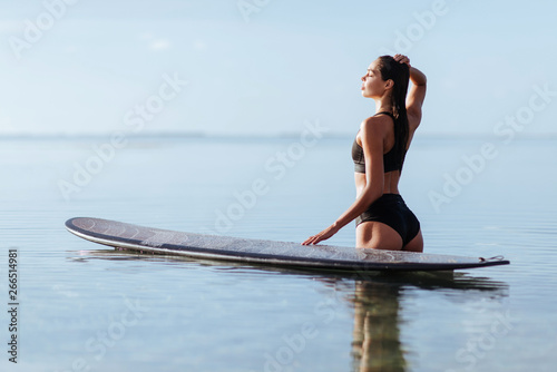 Beautiful girl on a surf board in the ocean. Girl with long hair in the ocean on the longboard.